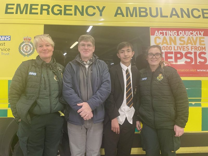 A patient and his father standing with two female ambulance crew.
