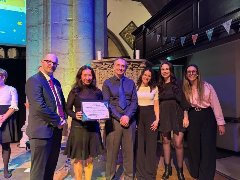 Six people standing posing for a photo holding a certificate
