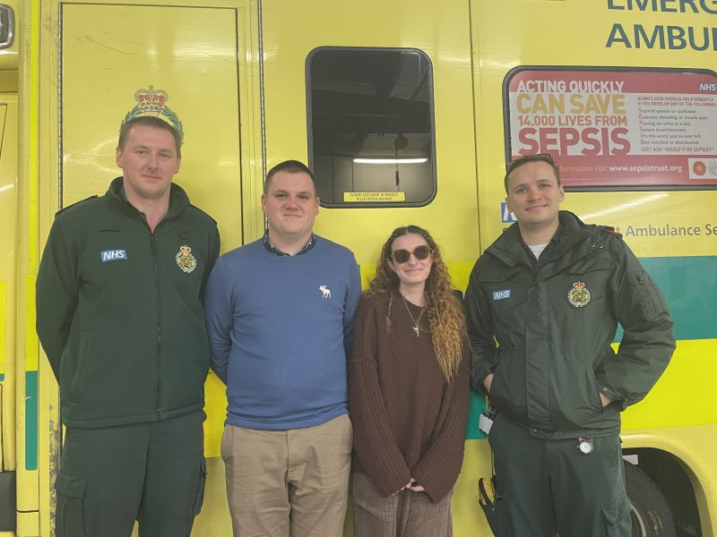 A female standing with three ambulance colleagues.