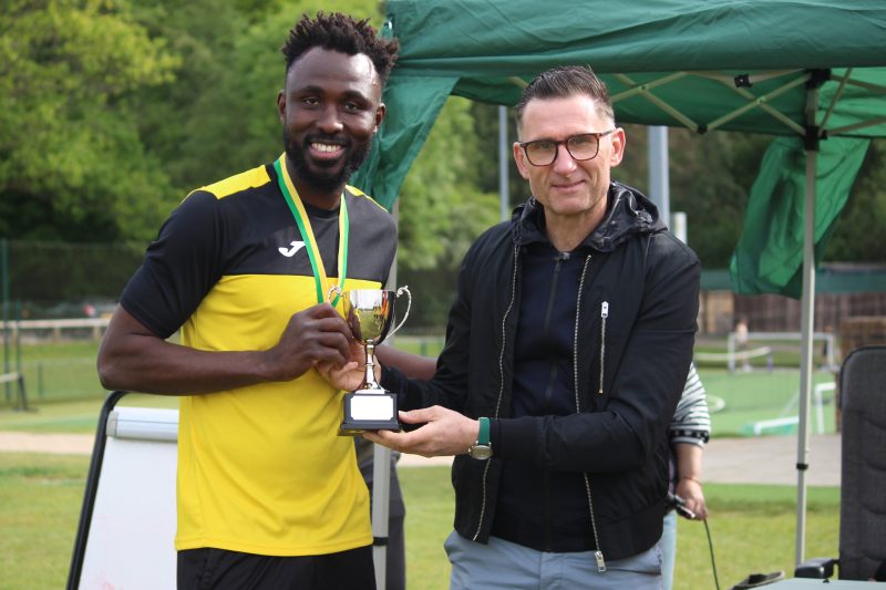 Sekou Souare holds the football trophy presented by former professional footballer Nick Forster on the right