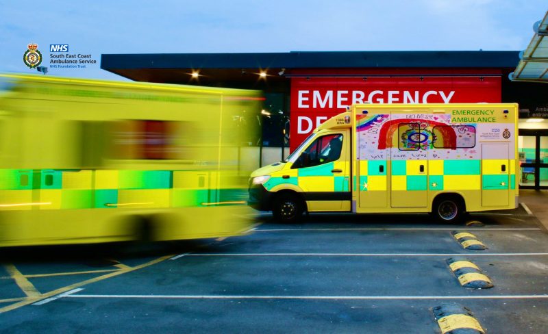 Two ambulance outside A&E with one vehicle not in focus as it drives away.