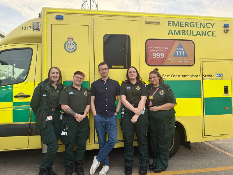 Five people standing up against an ambulance