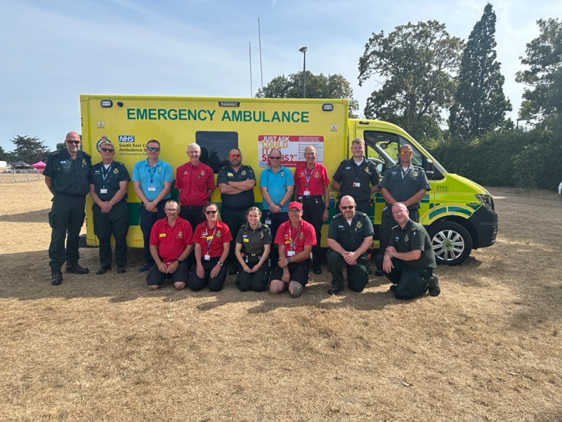Ambulance service staff and volunteers standing in front of ambulance