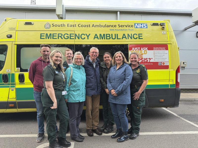 A family standing in front of an ambulance with clinicians in green uniform