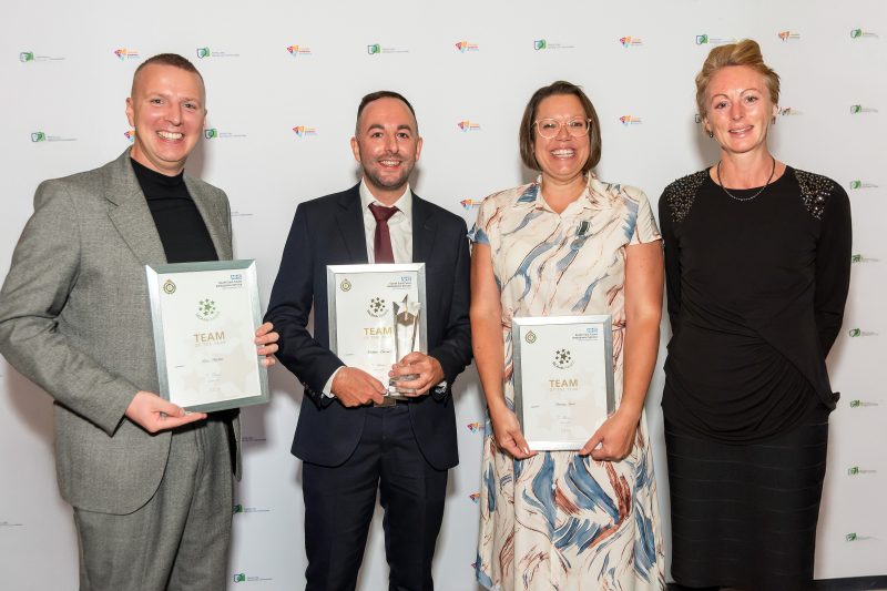 Frequent Caller Team, Ben, Nathan and Tammy stand holding their award certificates next to SECAmb Managing Director Jen