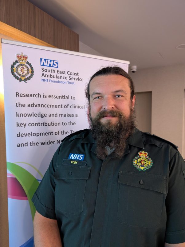 SECAmb paramedic, Thomas Whateley in front of reseach poster